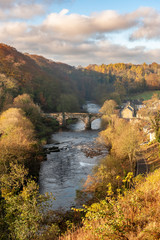 The Green Bridge over the River Swale as seen from the Castle Walk on a vibrant autumn afternoon in golden sunlight