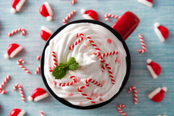 Peppermint coffee mocha decorated with candy canes for Christmas on blue background . Top view....