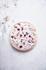 Whole cherry cake with almond petals and sugar powder on white background with cherry flowers.