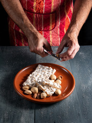 Obraz na płótnie Canvas male hands cracking almonds and plate with nougat