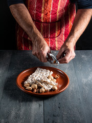 plate with nougat and hands of man cracking almonds