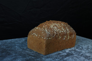 Fresh homemade rectangular bread on a dark background. Mother dough bread. Homemade bread sourdough, rustic baked bread. minimalism