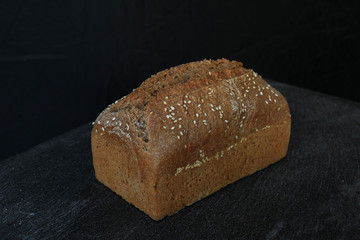 Fresh homemade rectangular bread on a dark background. Mother dough bread. Homemade bread sourdough, rustic baked bread. minimalism
