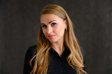 Close-up portrait of a pretty blonde girl with long curly hair standing in the studio on a gray background with emotions in different poses. Beauty, Model, Cosmetics