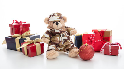 Cute teddy bear in soldier uniform and xmas presents isolated against white background
