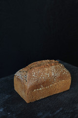 Fresh homemade rectangular bread on a dark background. Mother dough bread. Homemade bread sourdough, rustic baked bread. minimalism