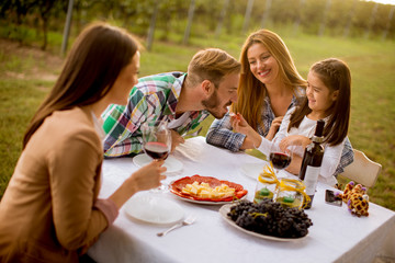 Young people enjoy dinner and wine tasting in the vineyard