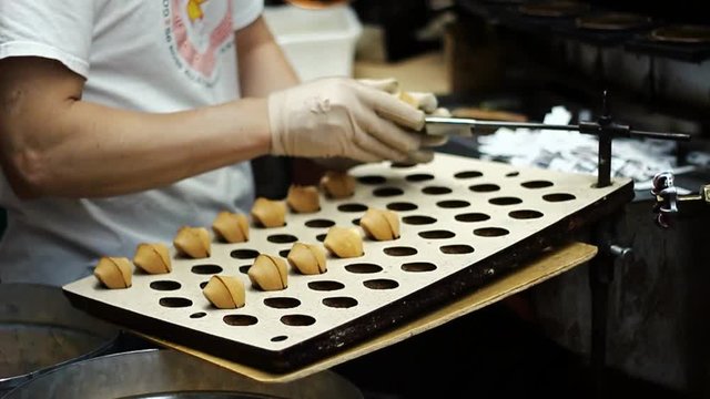 Woman Folding Fortune Cookies Fresh From Machine in San Francisco California