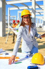 Happy beautiful female architect on construction site. She is smiling and satisfied with her job,...