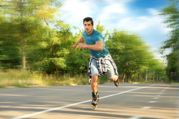 Handsome young man roller skating in park