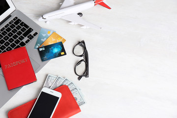 Smartphone, laptop, passport and money on light background, space for text. Travel agency