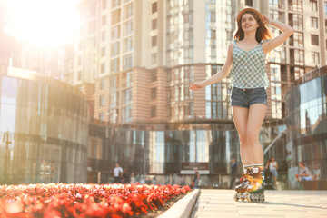 Beautiful young woman with roller skates having fun outdoors, space for text
