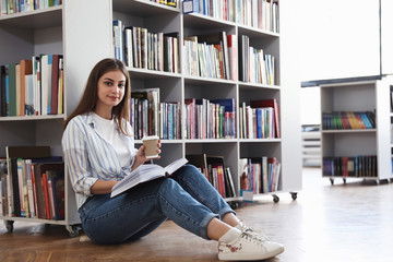 Young woman with book on floor in library