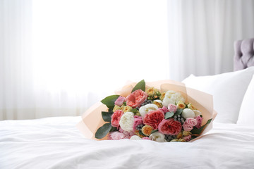 Beautiful flower bouquet on bed in light room. Space for text