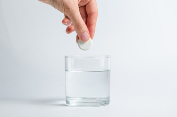 A hand holding effervescent soluble calcium tablet or vitamin C is placed in a glass of water. Health.The concept of a healthy lifestyle, prevention of vitamin deficiency. Isolated on white background