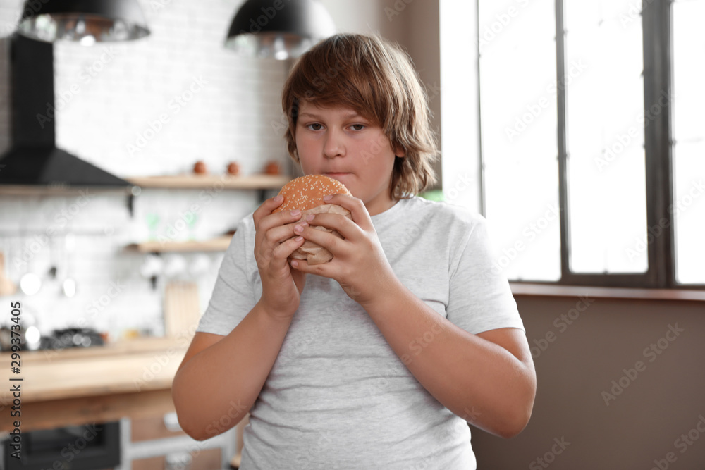 Canvas Prints Overweight boy with tasty burger in kitchen