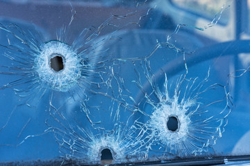 Bullet holes in the front safety glass of car. Close up view.