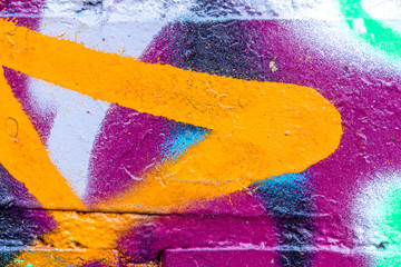 Fragment of colored graffiti painted on a brick wall.