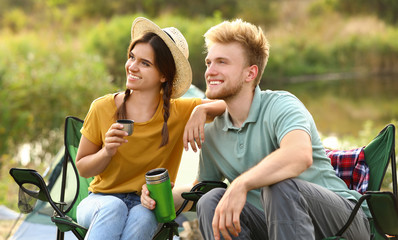 Obraz premium Young couple with hot drinks resting outdoors. Camping vacation