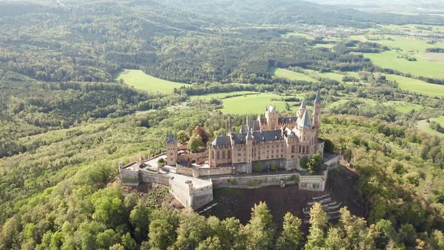 Aerial panorama of Burg Hohenzollern (Hohenzollern castle) with hills and villages surrounded by forests with beautiful foliage