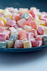 Turkish Turkish delight multicolored on a dark blue plate.