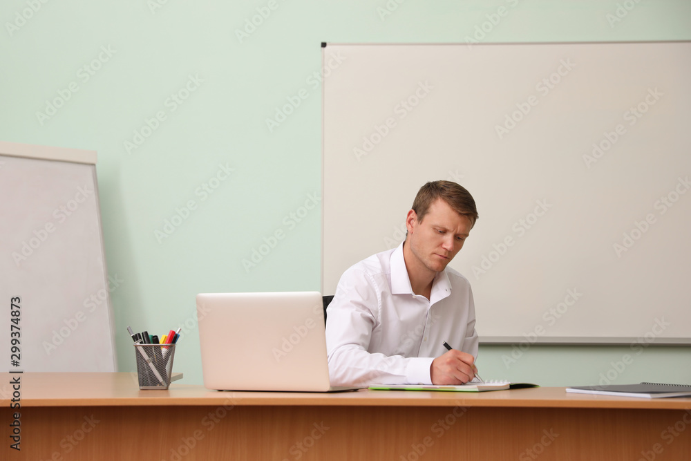 Wall mural Male teacher at his desk in classroom