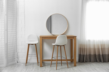 Makeup room interior with wooden table and mirror near white wall