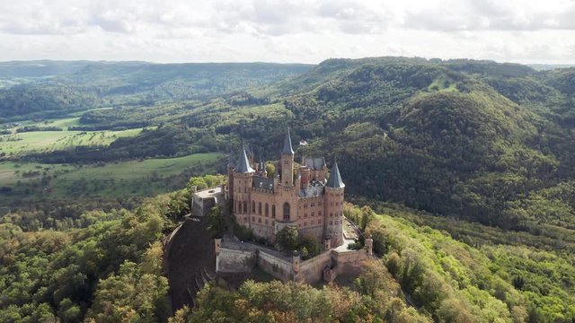 Aerial panorama of Burg Hohenzollern (Hohenzollern castle) with hills and villages surrounded by forests with beautiful foliage