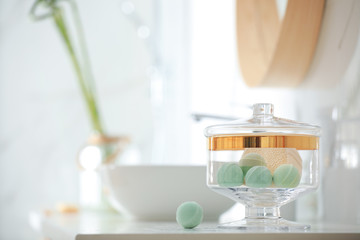 Fototapeta na wymiar Jar with bath bombs and bath sponge on white countertop indoors