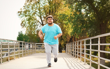 Young overweight man running outdoors. Fitness lifestyle