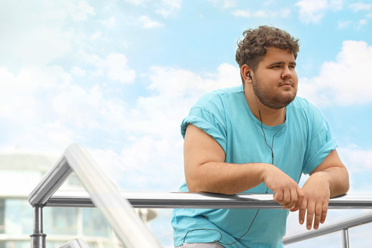 Young Overweight Man Leaning On Railing Outdoors