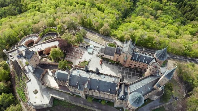 Aerial panorama of Burg Hohenzollern (Hohenzollern castle) with hills and villages surrounded by forests with beautiful foliage