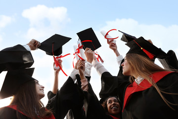 Group of students with diplomas outdoors. Graduation ceremony