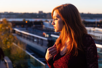 Woman with red hair outside in warm, evening light