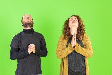 Beautiful young people over green isolated background praying with hands together asking for forgiveness smiling confident.