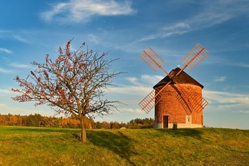 Fototapeta na wymiar Beautiful autumn landscape with old windmill at sunset and beautiful blue sky with clouds. Colorful nature background on autumn season. Chvalkovice - Czech Republic.