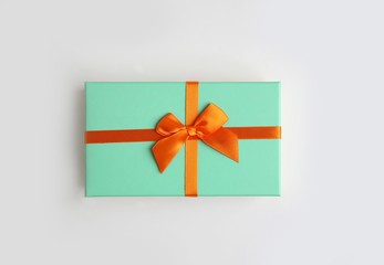 Mint color gift box with orange ribbon on white background. Isolate, copy space.