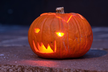 Smiling and shining Halloween pumpkin in the dark lying on the ground. Seen in Germany, Bavaria, in October.