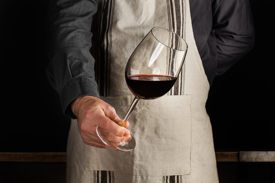 Hombre camarero sosteniendo una copa de vino tinto en movimiento. Sommelier. Vista de frente	