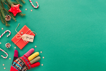 Creative Christmas flat lay background in green and red on green paper with copy-space. Hand in...
