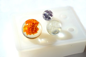 Dried flowers in epoxy resin balls. Silicone mold isolated on white background. 