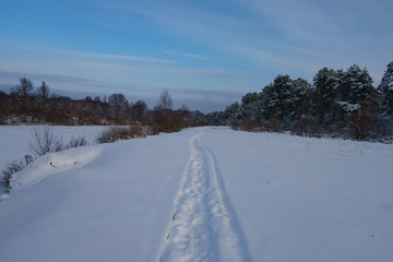 Cold snow white Russian winter. Narrow footpath in deep snow along the banking of the river Desna. The concepts of beauty of nature and ecological tourism.