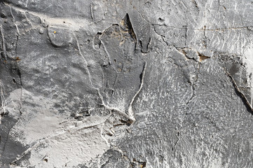 The texture of gypsum or alibaster cracked plaster on the wall is a thick layer. Gradient gray...