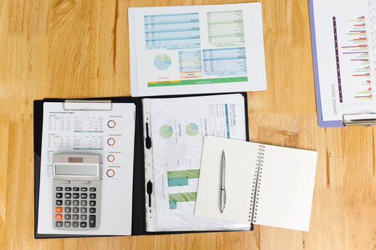 Top view of business charts or graphs, calculatornotebook and pen on desk.