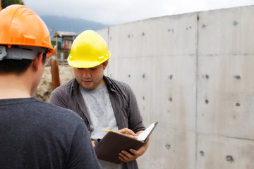 Team of construction workers discussing project details with blueprint in construction site.