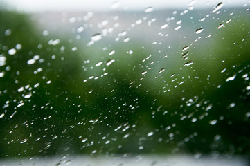 Natural background Drops on both sides of the glass from the rain and from the fogging abstract view, raindrops against the blue glass and the blurred landscape of the gradient of blue and green