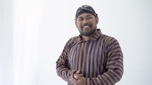 asian man with javanese traditional cloth lurik greeting and smiling to camera