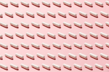 Obraz premium Trendy pattern made with Pharmaceutical medicine pills, tablets and capsules on bright light pink background. Medicine creative concepts. Minimal style with colorful paper backdrop. Trendy colors