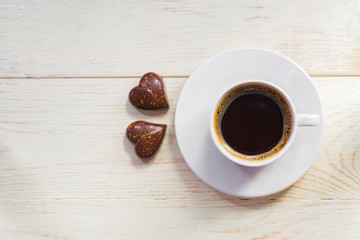  two  heart shape chocolates and  cup of coffee on wooden table. valentine's day celebration concept. Top view