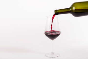 red wine pouring into glass isolated on white background